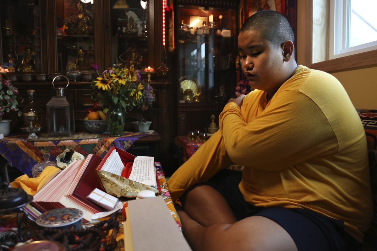 Jalue Dorje, 14, says his morning prayers, Tuesday, July 20, 2021, in Columbia Heights, Minn. When he was an infant, Jalue, now 14, was identified as the eighth reincarnation of the lama Terchen Taksham Rinpoche. After finishing high school in 2025, Jalue will head to northern India and join the Mindrolling Monastery, more than 7,200 miles (11,500 kilometers) from his home. (AP Photo/Jessie Wardarski)
