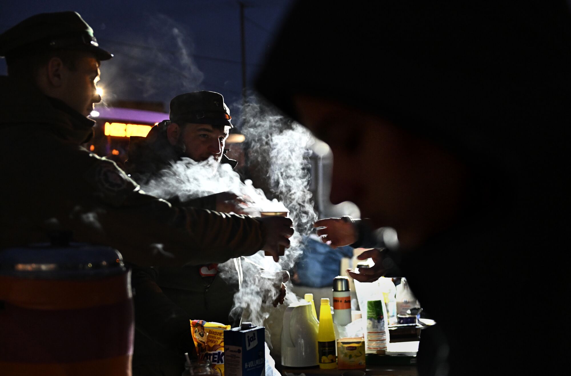 Volunteers serve coffee to Ukrainian refugees on a cold evening in Medyka, Poland.