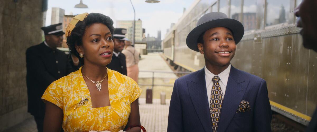 A woman in a yellow dress next to a boy in a hat. 