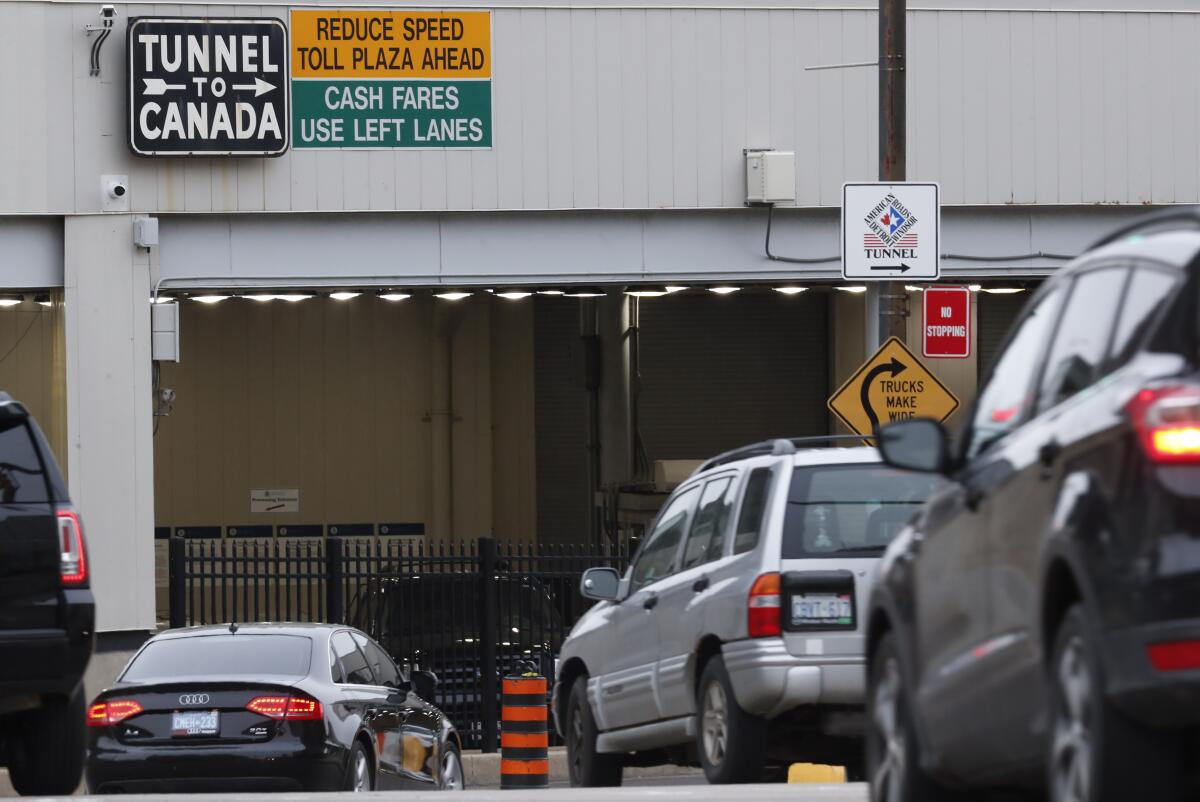 Cars line up at a structure with the sign "Tunnel to Canada"