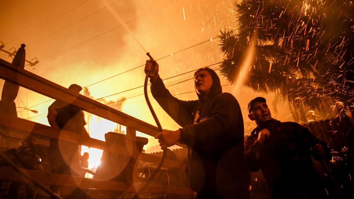 Embers fly around Brandon Baker, center, and Prescott McKenzie, right, during a 2017 wildfire in Ventura. New guidelines are intended to give residents more warning of approaching fires and extreme weather.