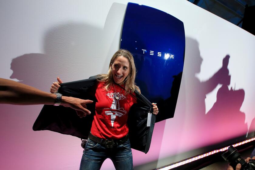 Carrie Lederer, a Santa Monica resident and Tesla car owner, poses with the Powerwall during an event at the company's plant in Hawthorne on Thursday.