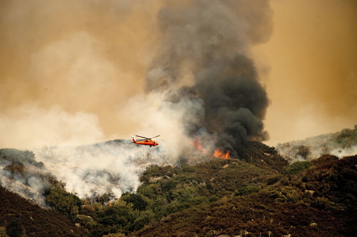 A helicopter prepares to drop water on the KNP Complex Fire in Sequoia National Park, Calif., on Wednesday, Sept. 15, 2021. The blaze is burning near the Giant Forest, home to more than 2,000 giant sequoias. (AP Photo/Noah Berger)