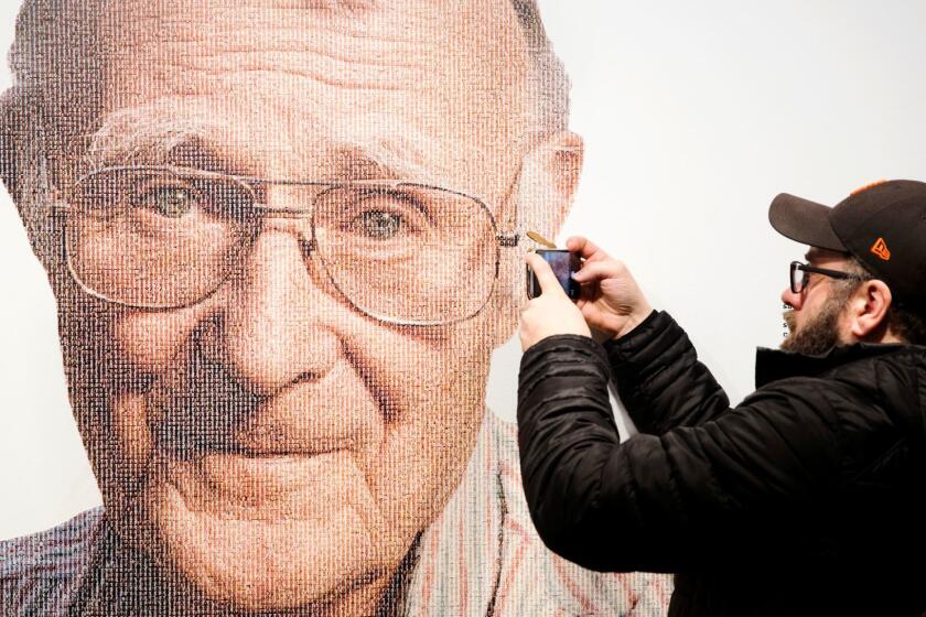A visitor takes a photo of founder of Swedish multinational furniture retailer IKEA, Ingvar Kamprad, at the IKEA museum, in Almhult, Sweden, on Sunday Jan. 28, 2018. The portrait of Kamprad on the wall is made out of a big amount of small portraits of employees. Kamprad died Saturday Jan. 27, aged 91. (Ola Torkelsson/TT via AP)