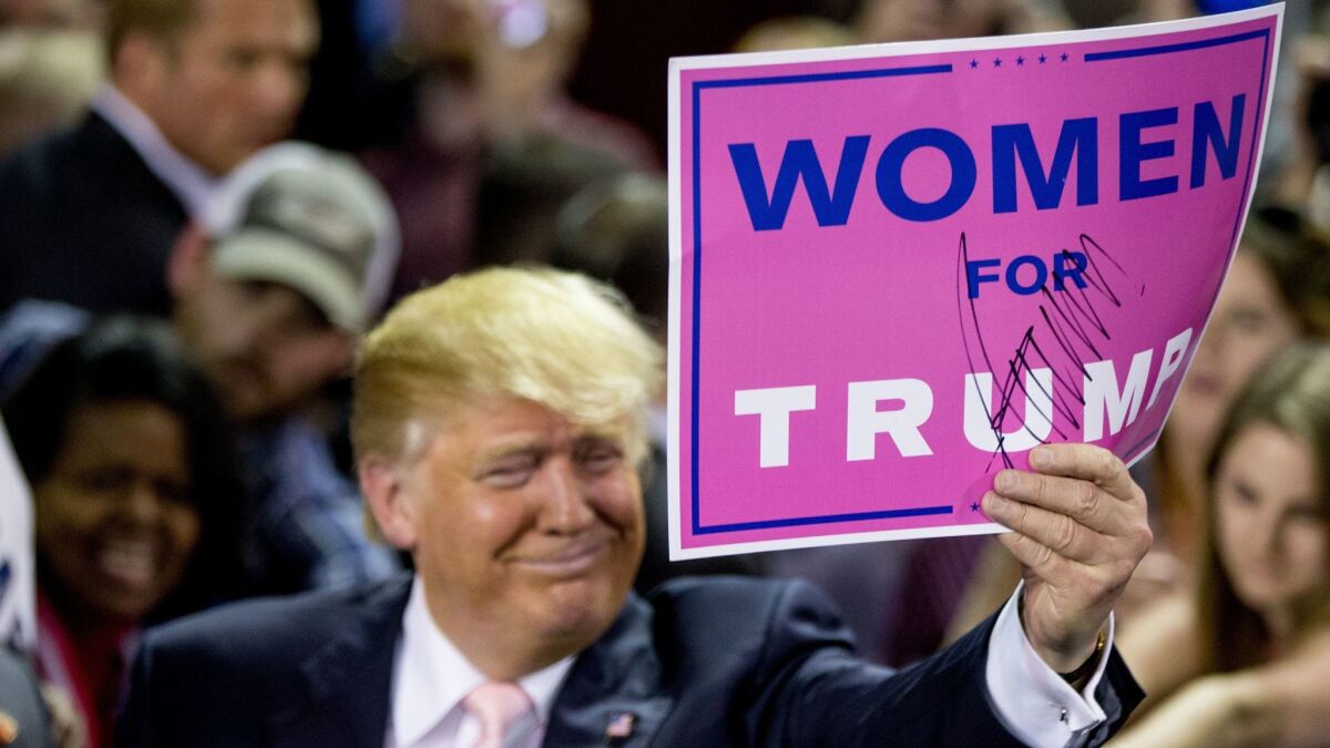Then presidential candidate Donald Trump holds a campaign sign that reads "Women for Trump" after speaking at a rally in Valdosta, Ga. on Feb. 29, 2016.