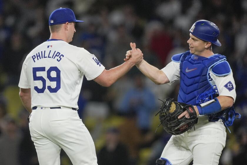Los Angeles Dodgers relief pitcher Evan Phillips, left, celebrates with catcher Will Smith after the team's win in a baseball game against the San Francisco Giants, Tuesday, April 2, 2024, in Los Angeles. (AP Photo/Ryan Sun)
