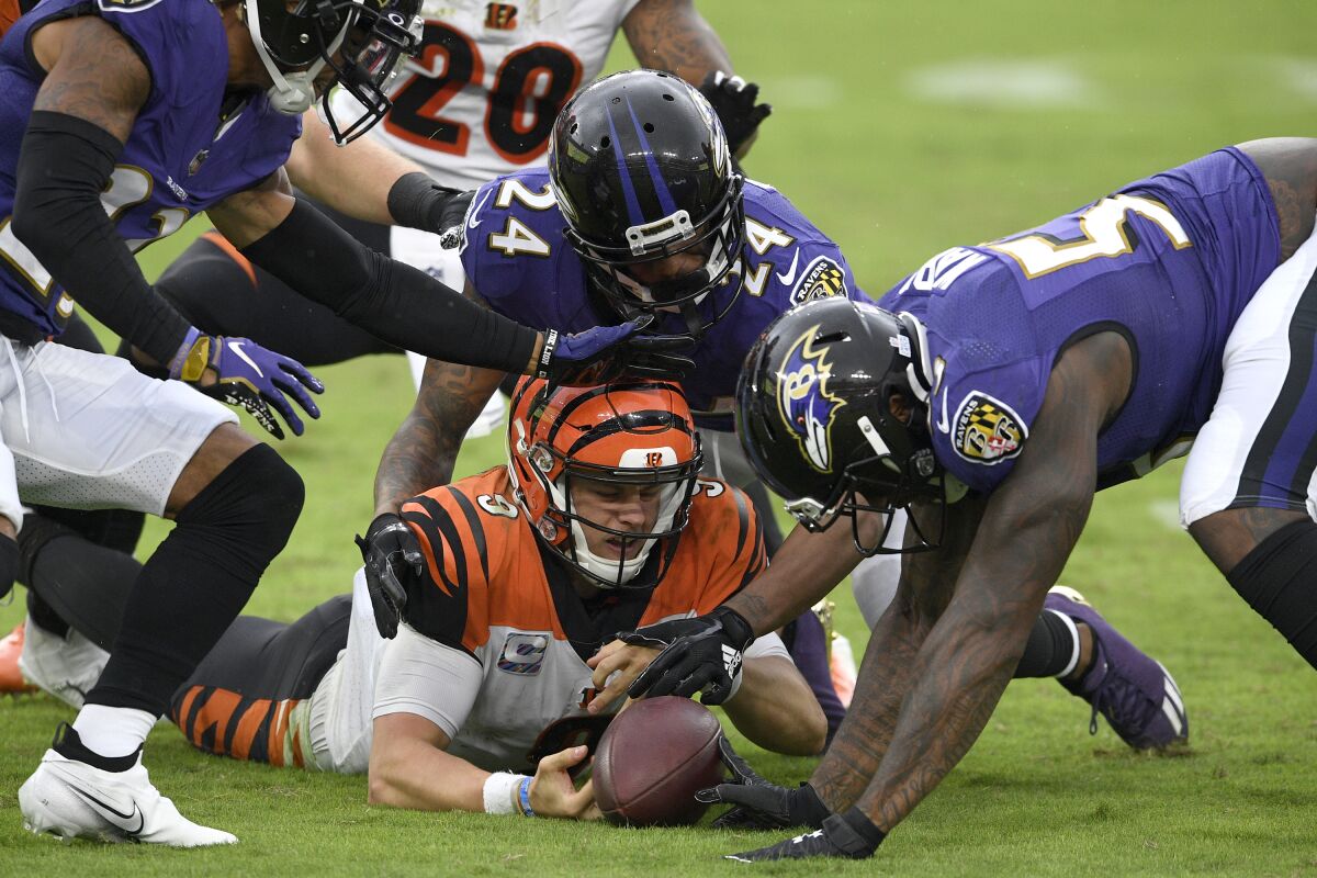 Bengals quarterback Joe Burrow fumbles as Ravens cornerback Marcus Peters (24) and defensive end Jihad Ward try to recover.