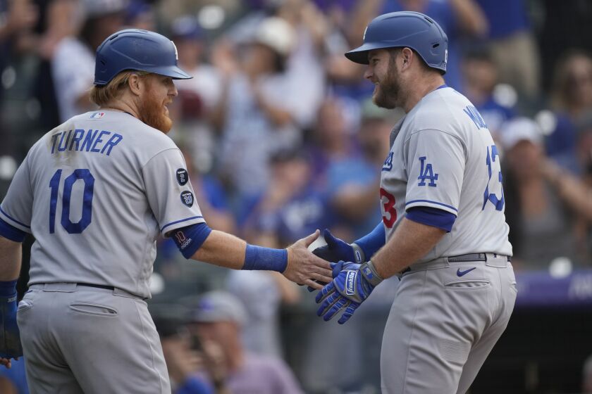 Los Angeles Dodgers' Justin Turner, left, congratulates Max Muncy who crossed home plate following his two-run home run off Colorado Rockies relief pitcher Lucas Gilbreath in the 10th inning of a baseball game Thursday, Sept. 23, 2021, in Denver. (AP Photo/David Zalubowski)
