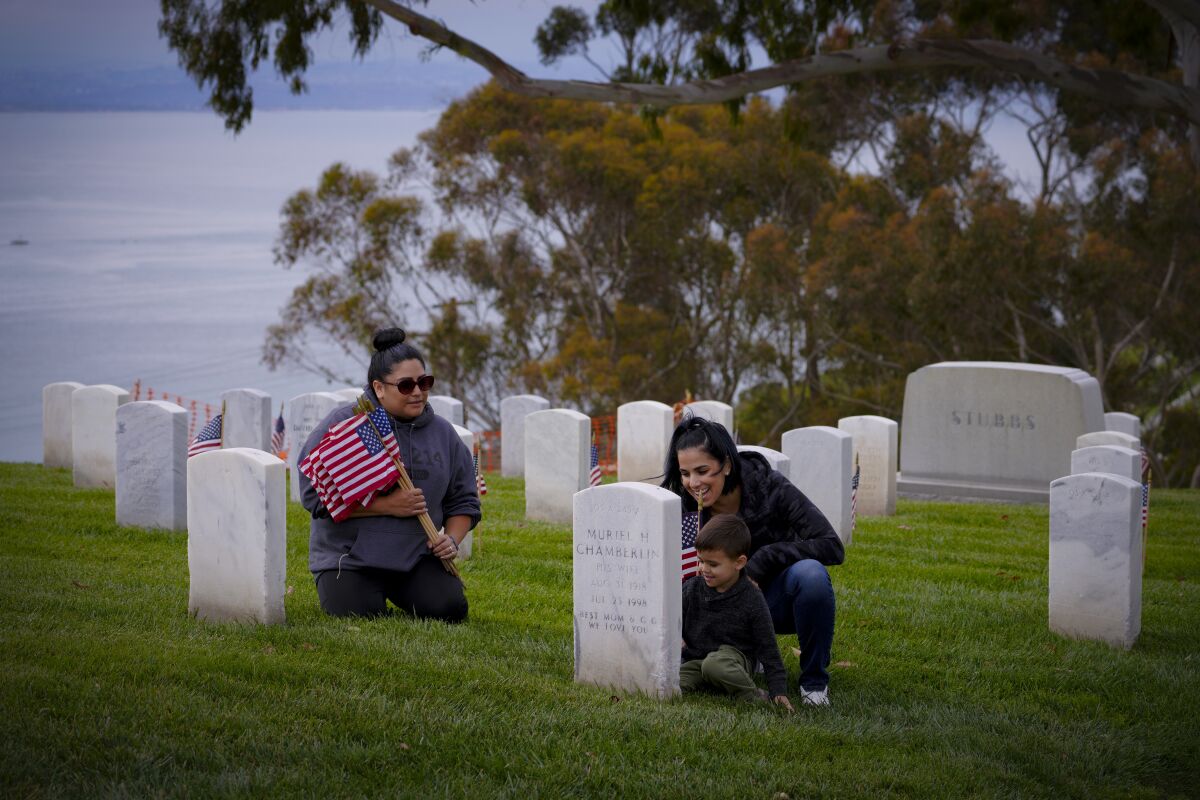 Jennifer Zgoda of Spring Valley examines one of the headstones at Fort Rosecrans National Cemetery with her son, Maximus, 3.
