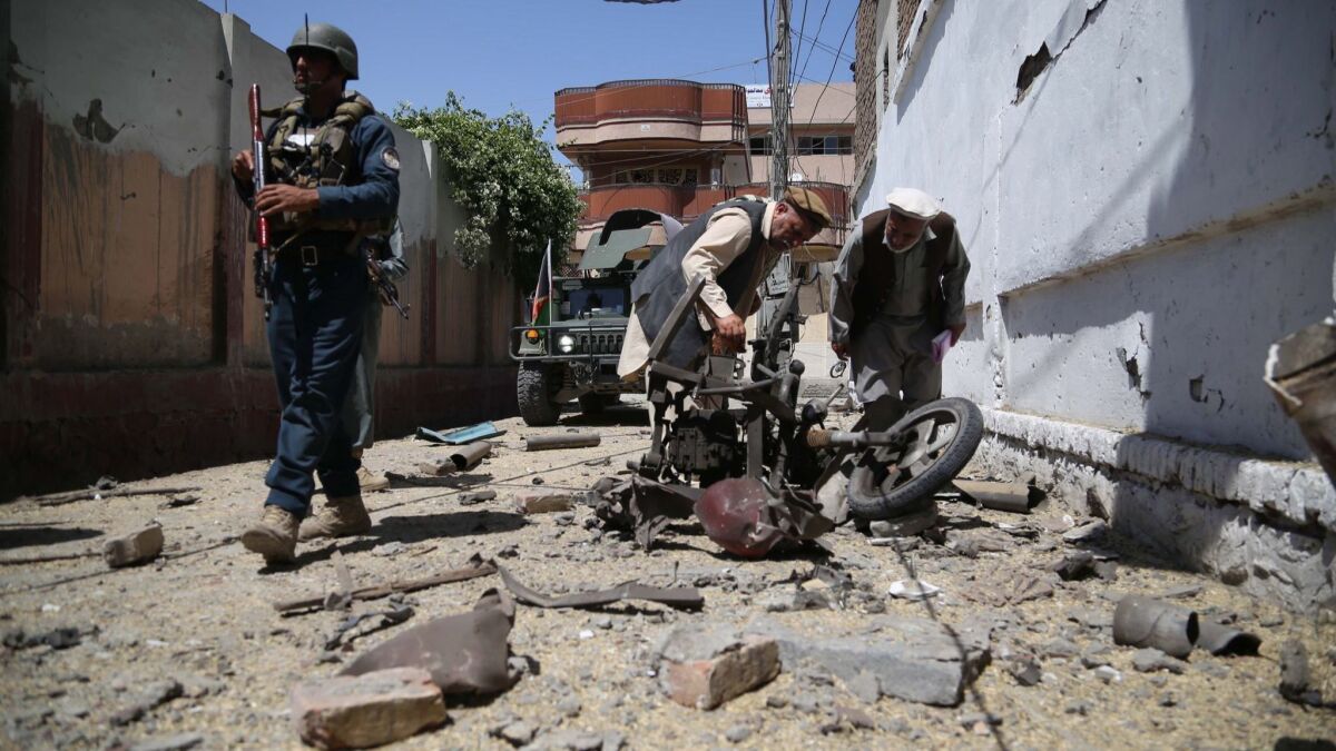 Afghan security officials inspect the scene of a bomb blast near a voter registration center in Jalalabad.