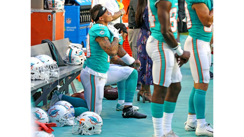 Miami Dolphins receivers Kenny Stills and Albert Wilson kneel during the national anthem as they prepare to play the Tampa Bay Buccaneers at Hard Rock Stadium in Miami Gardens, Fla., on Thursday.