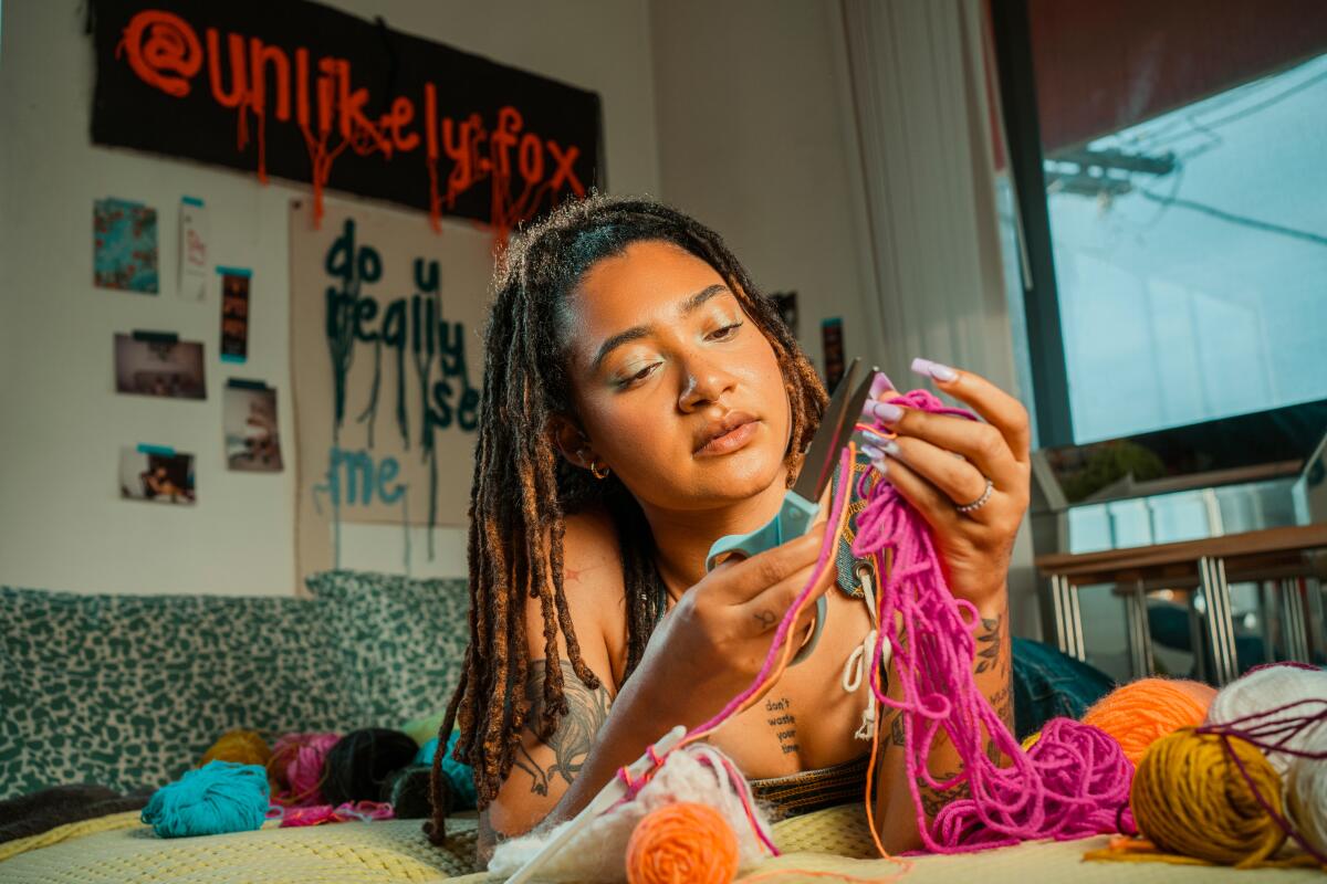 A woman crochets on a bed 