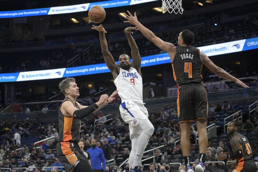Los Angeles Clippers center Serge Ibaka (9) passes the ball between Orlando Magic center Moritz Wagner (21), left, and guard Jalen Suggs (4) during the first half of an NBA basketball game, Wednesday, Jan. 26, 2022, in Orlando, Fla. (AP Photo/Phelan M. Ebenhack)