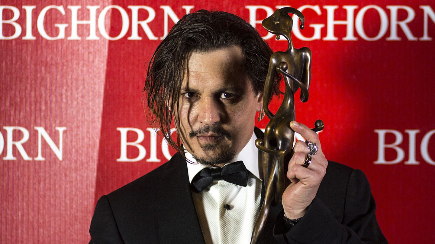 Johnny Depp shows the world his Desert Palm Achievement Award.