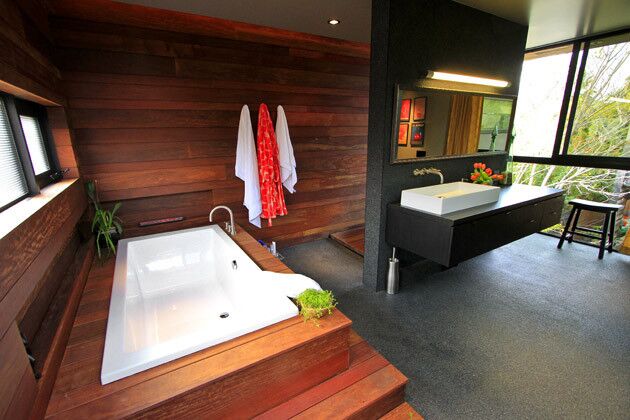 The master bathroom, which like the rest of the house is defined by its free-flowing space, clean lines and warm finishes. The wood paneling and bath surround is ipe, a sustainable hardwood often used in decking.
