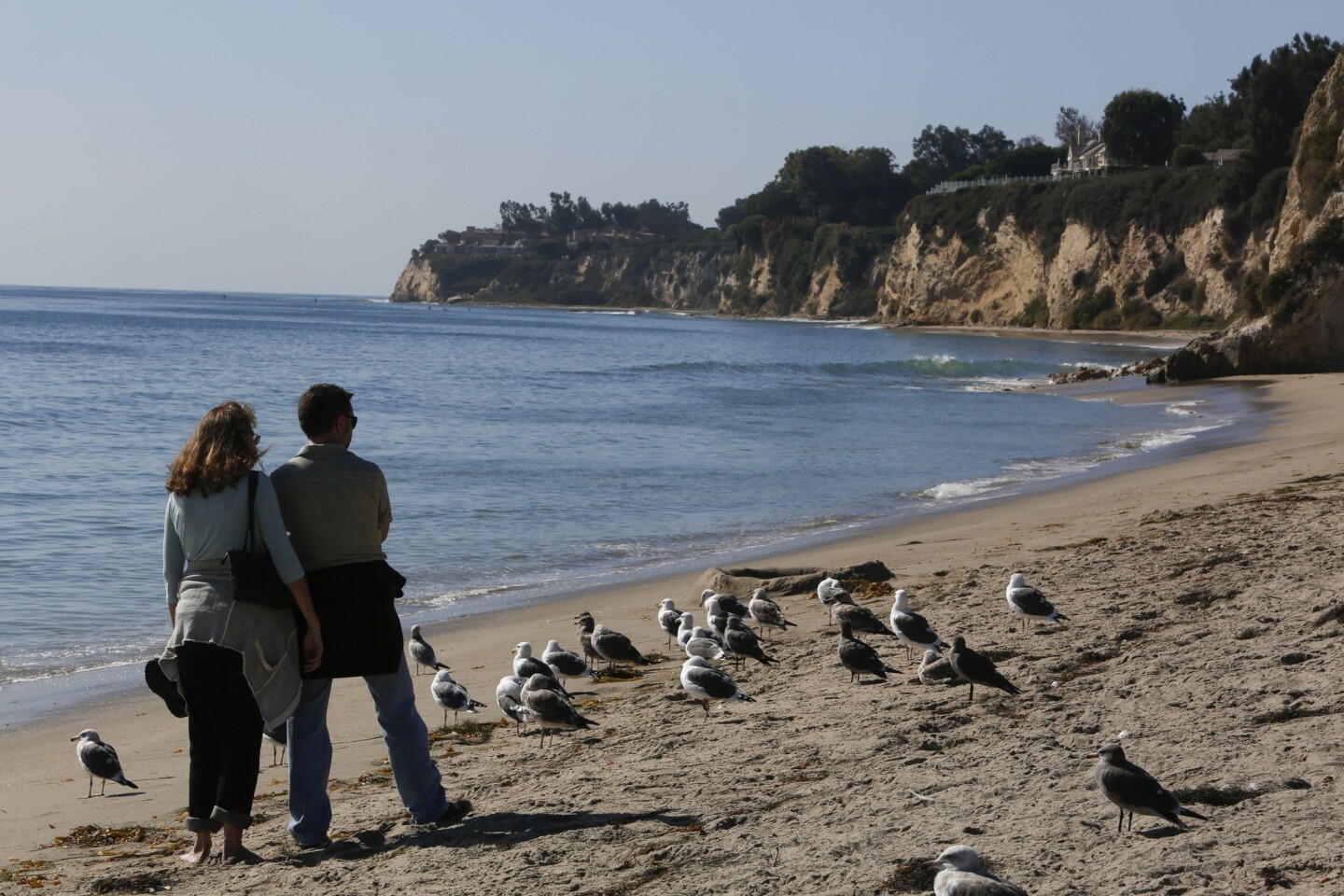 A couple strolls along the beach at Malibu's Paradise Cove. The Coastal Commission is looking into complaints that public access is restricted.
