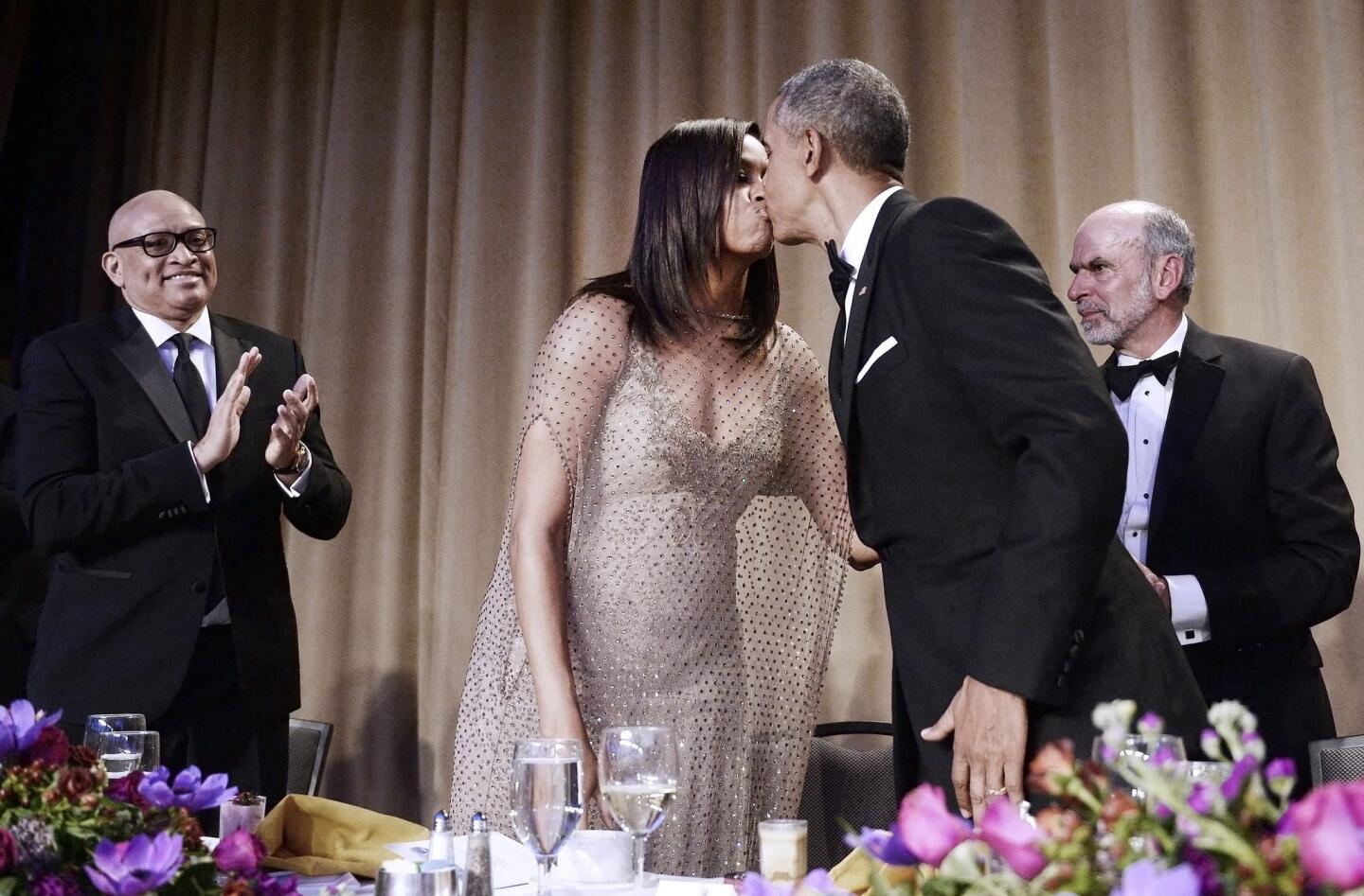 President Obama kisses First Lady Michelle Obama after delivering a speech as host-comedian Larry Wilmore, left, applauds during the White House Correspondents' Association dinner.