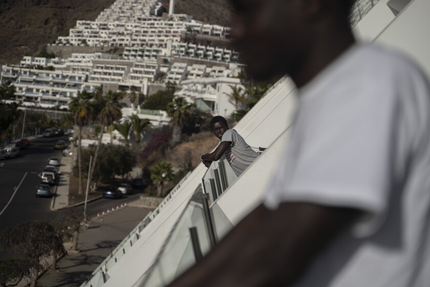 A migrant leans on the balcony of the Holiday Club Puerto Calma hotel in Puerto Rico de Gran Canaria, Spain, April 2, 2021. With hundreds of empty rooms, British hotel director Calvin Lucock and his Norwegian wife Unn Tove Saetran decided to reopen their doors at their own expense to provide food, shelter and care to young migrant men who fell out of the official reception and integration system. (AP Photo/Renata Brito)
