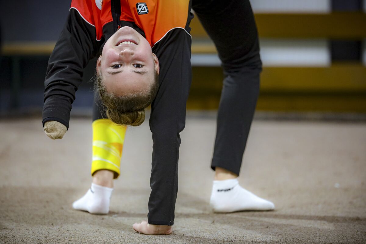 Sara Becarevic warms up before performing a gymnastics routine in Visoko, Bosnia, Wednesday, Dec. 1, 2021. In Bosnia, a poor, Balkan country which habitually marginalizes people with disabilities, a soon-to-be-14-year-old girl, born without her lower left arm, pursues her dream of becoming an internationally recognized rhythmic gymnast. Sara Becarevic says she got enchanted with the demanding sport as a toddler, while watching the world championships on television. (AP Photo)