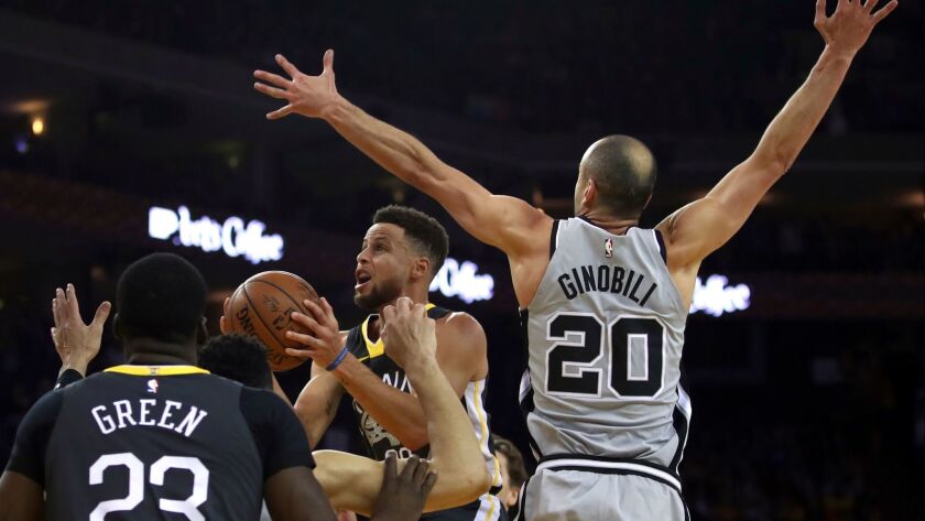 Golden State Warriors' Stephen Curry, center, looks to shoot past San Antonio Spurs' Manu Ginobili (20) during the first half.