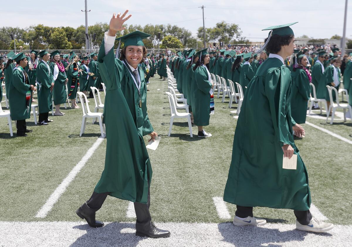A graduate waves at Costa Mesa High School's commencement ceremony.
