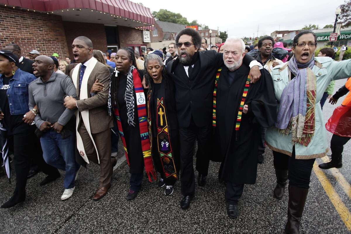 Cornel West, center, joins clergy members and other demonstrators Monday to protest the shooting of Michael Brown in Ferguson, Mo.