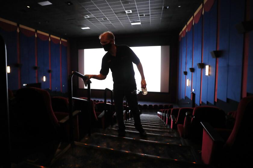 LA MESA, CA - SEPTEMBER 3: Wayne Price cleans handrails in a movie theater on the first day of being open since the closing due to the coronavirus pandemic at Reading Cinemas Grossmont on Thursday, Sept. 3, 2020 in La Mesa, CA. (K.C. Alfred / The San Diego Union-Tribune)
