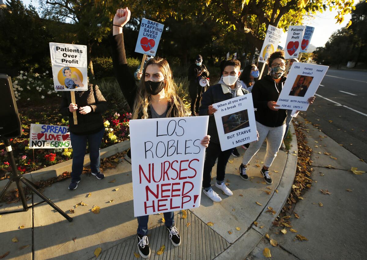 Medical professionals hold signs during a street-corner protest.