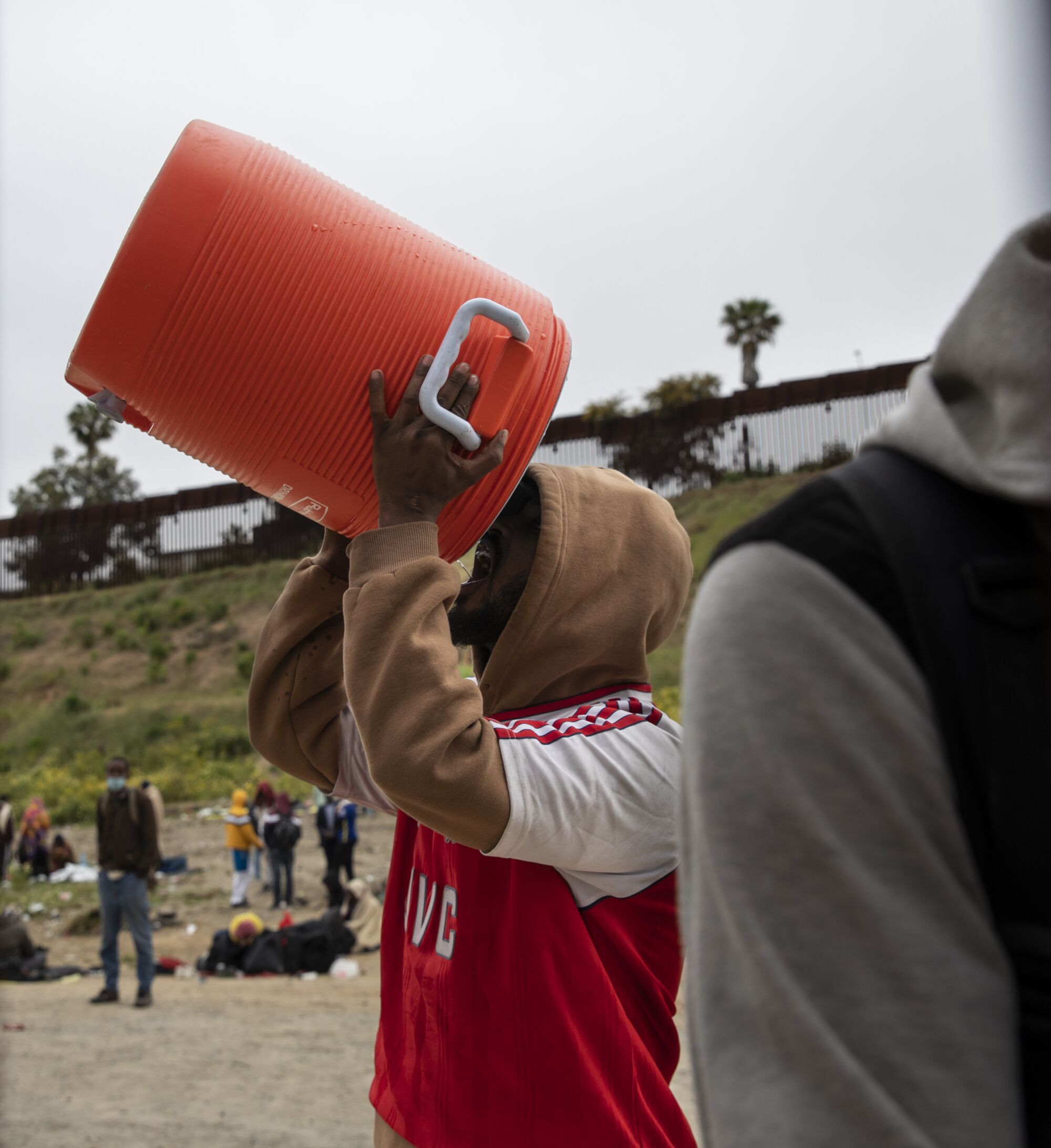 Un migrante muestra al fotógrafo que un garrafón de agua vacio