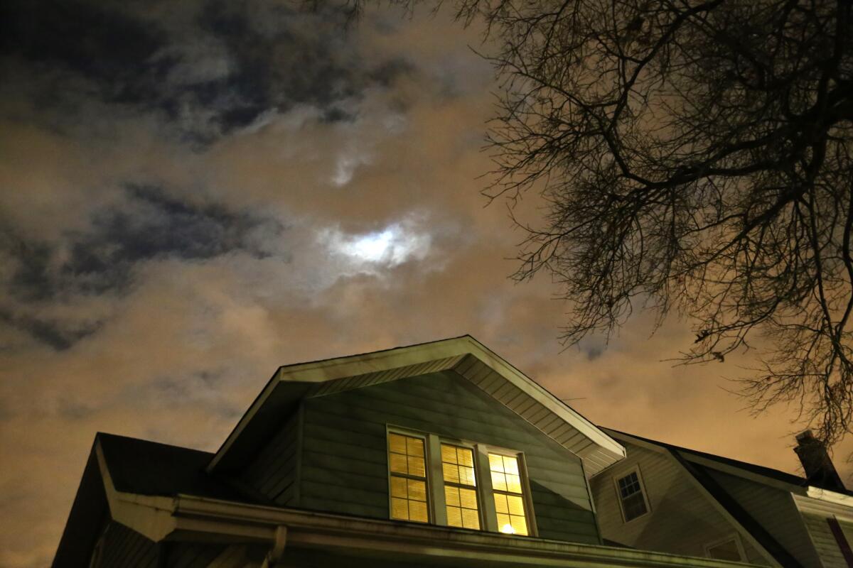 Photograph of a house at night with a cloudy sky.
