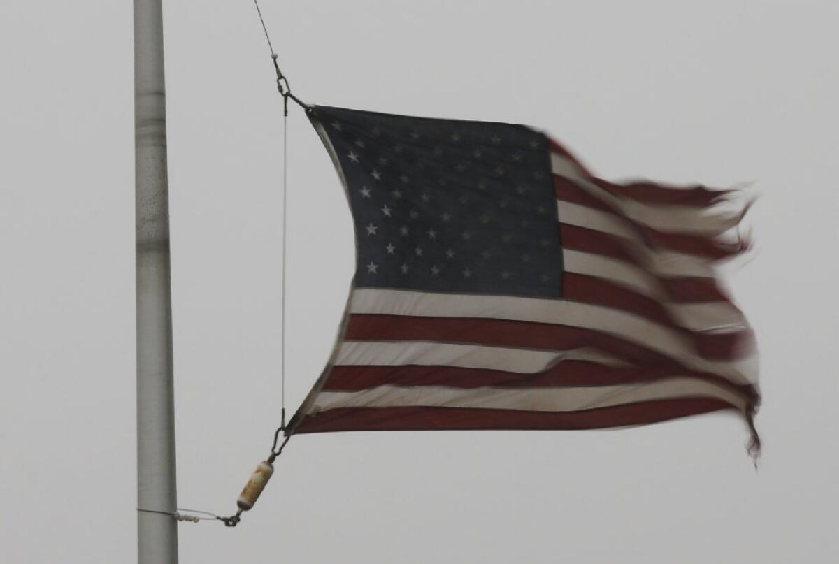 Strong winds whip a tattered U.S. flag at a farm credit office near Baldwin City, Kan.
