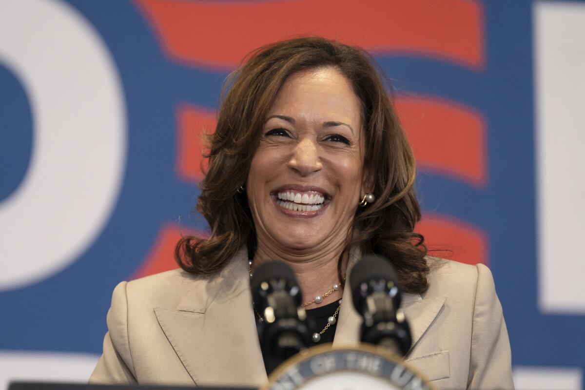 Kamala Harris grins as she stands at a podium.