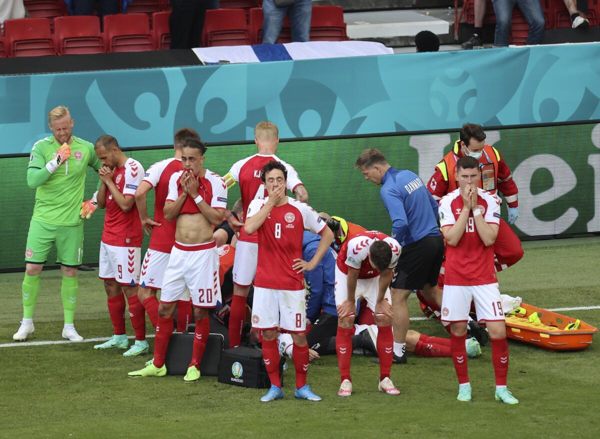 Denmark's players react as teammate Christian Eriksen lays on the ground after a heart attack.