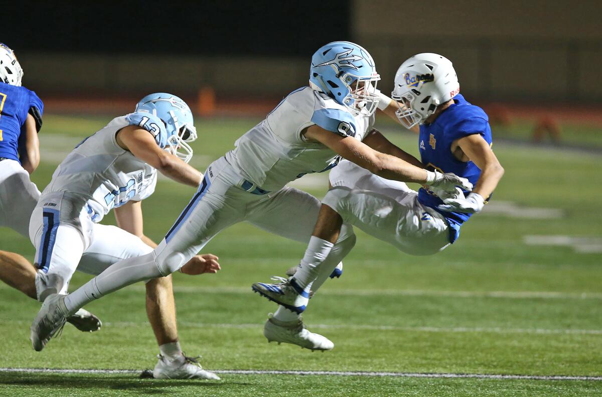 Corona del Mar's Carter Duss hits Fountain Valley's James Martinez as Martinez tries to get a punt off in a Sunset League game on Oct. 17 at Huntington Beach High.