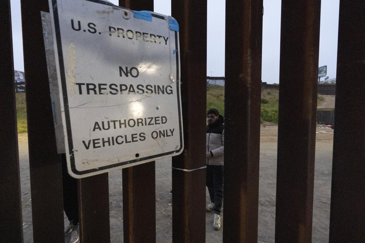 Migrantes esperan entre las vallas fronterizas que separan a Tijuana, México, de San Diego, EEUU, 