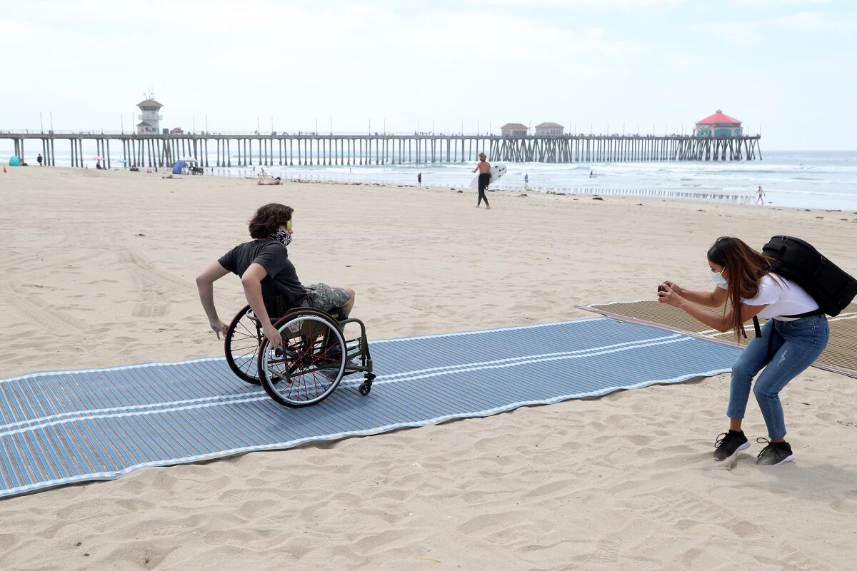 Adaptive surfer Kumaka Jensen rolls out on the first Mobi-Mat in Huntington Beach on  May 5, 2021.