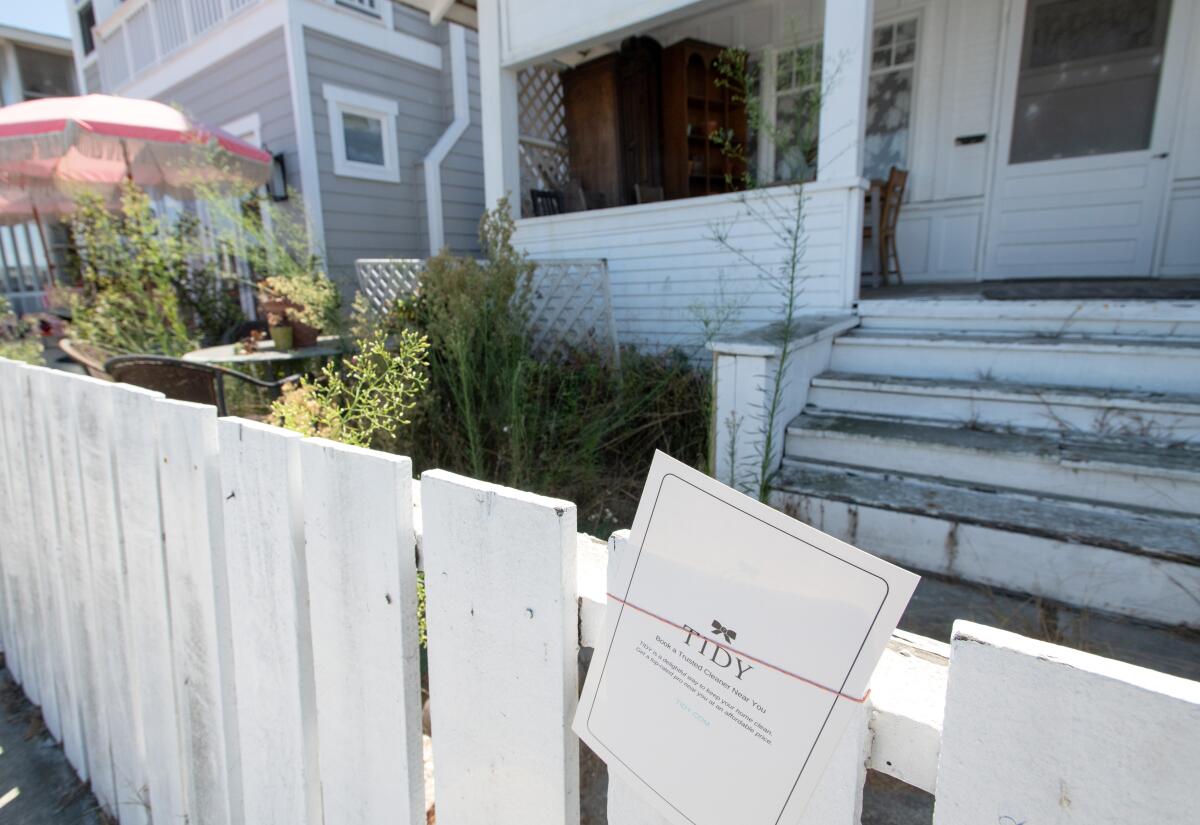 An ad for cleaning services is posted on the fence of a home with overgrown weeds on Balboa Boulevard.