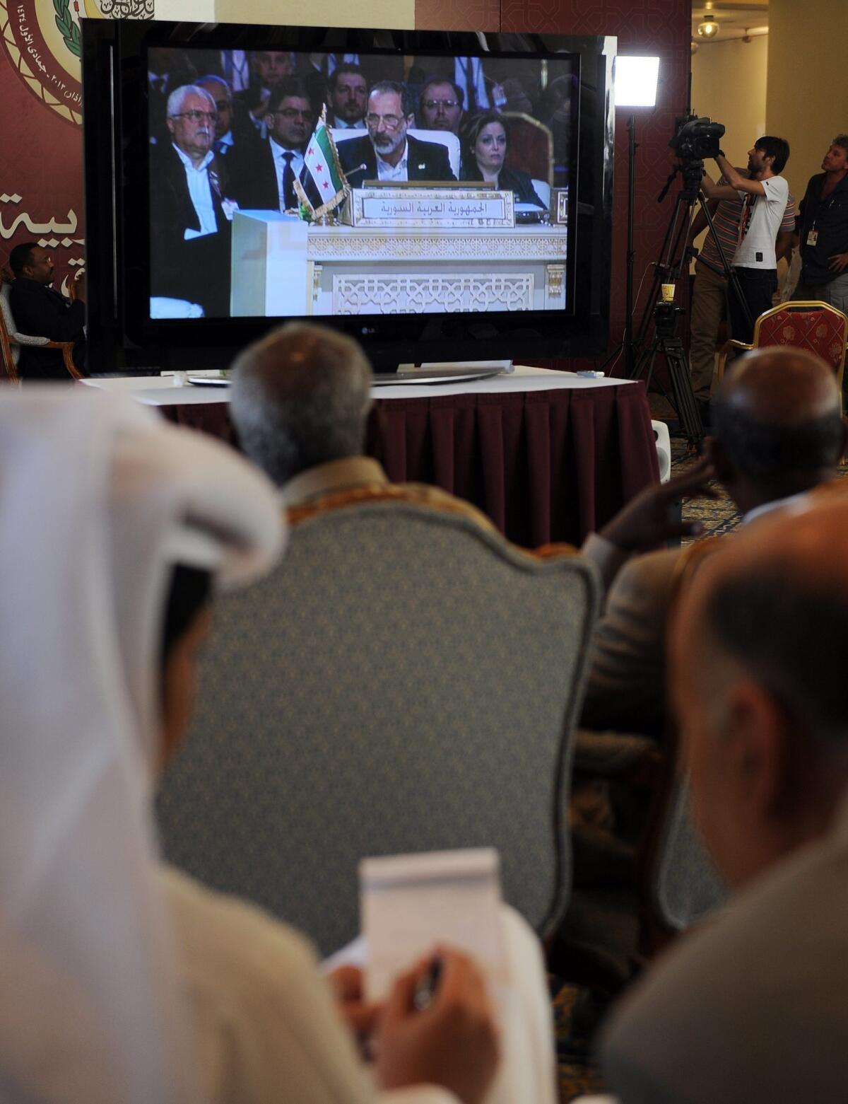 Members of the news media watch a live video feed of Syrian opposition leader Moaz Khatib speaking to the opening session of the Arab League summit in Doha, Qatar, on Tuesday. The Syrian opposition was handed Syria's seat in the Arab League.