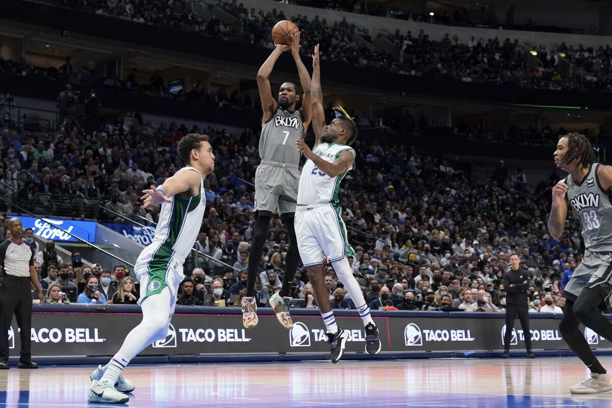 Dallas Mavericks' Dwight Powell, left, and Reggie Bullock, right, defend as Brooklyn Nets forward Kevin Durant (7) takes a shot in the second half of an NBA basketball game in Dallas, Tuesday, Dec. 7, 2021. (AP Photo/Tony Gutierrez)