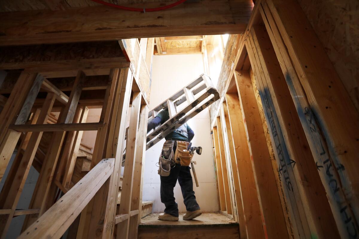 A worker carries a ladder inside a home under construction.