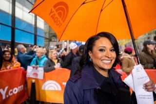Kristen Welker smiling while holding an orange umbrella and some papers in front of a crowd