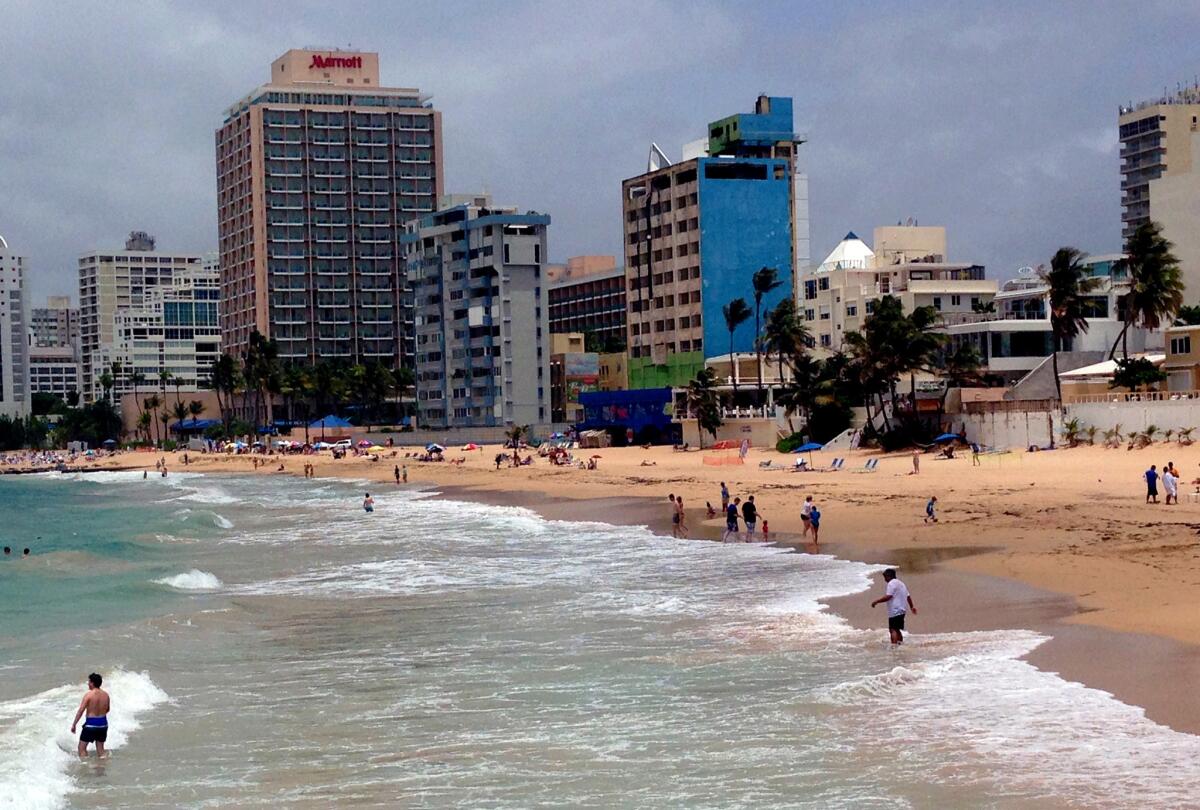 Beach-goers enjoy the surf in San Juan's Condado district, but experts say Puerto Rico's financial crisis is due in part to its failure to build up its tourist industry and capitalize on its Caribbean locale.