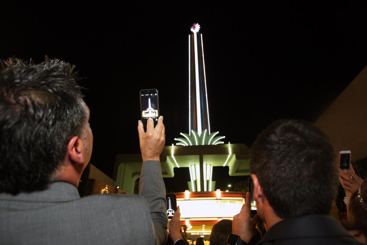 In this Sept. 2015 photo, guests to the Alex Theatre in Glendale use their cell phones to record photos and video of the lighting of the spire and starburst as part of the 90th anniversary of the theater.