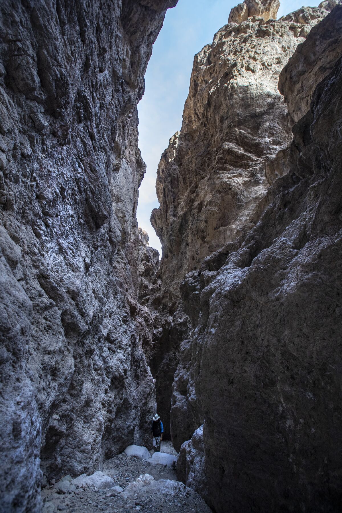 A hiker climbs into the slot canyon.