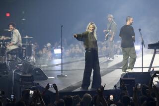 Four band members standing on a round stage