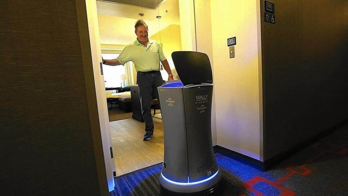 William Savoie, de Burlington (Vermont), le abre la puerta a Wally, un botones robot, que le entrega su orden de dos botellas de agua en su habitación del Residence Inn by Marriott, en el Century Boulevard de Los Ángeles. El robot puede entregar cosas pequeñas como toallas, bocadillos y café a huéspedes del hotel.