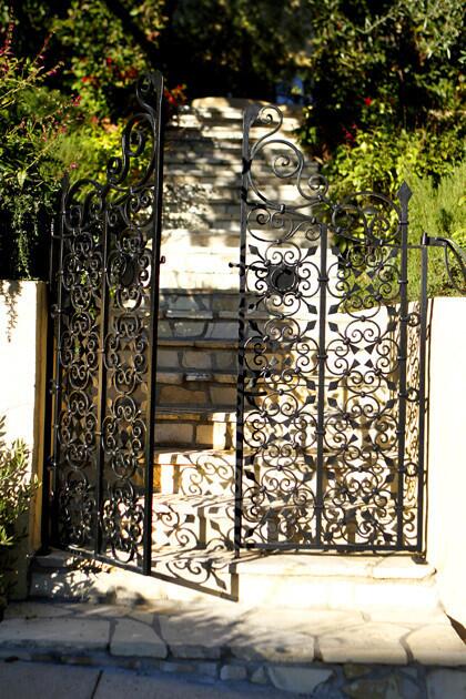 Daigre's first move was to redo the aging entry staircase by widening it and paving it with new flagstone. The homeowners looked at many wrought-iron gates before settling on the scrollwork for the entry by the street. The design was actually copied from a gate at another Spanish house in the neighborhood, then enlarged to fit this house.