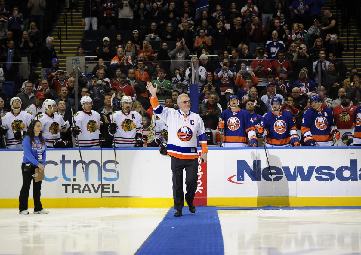 FILE - Former New York Islander Clark Gillies waves to fans before he dropped a ceremonial puck before the Islanders' NHL hockey game against the Chicago Blackhawks at Nassau Coliseum on Dec. 13, 2014, in Uniondale, N.Y. Gillies, a stalwart on the Islanders' dynasty that won four straight Stanley Cup championships in the early 1980s, has died. He was 67. The Islanders announced Gillies' death Friday night, with team president and general manager Lou Lamoriello saying “the entire Islanders community is devastated by the loss.” The team did not say where Gillies died or provide a cause of death. (AP Photo/Kathy Kmonicek, File)