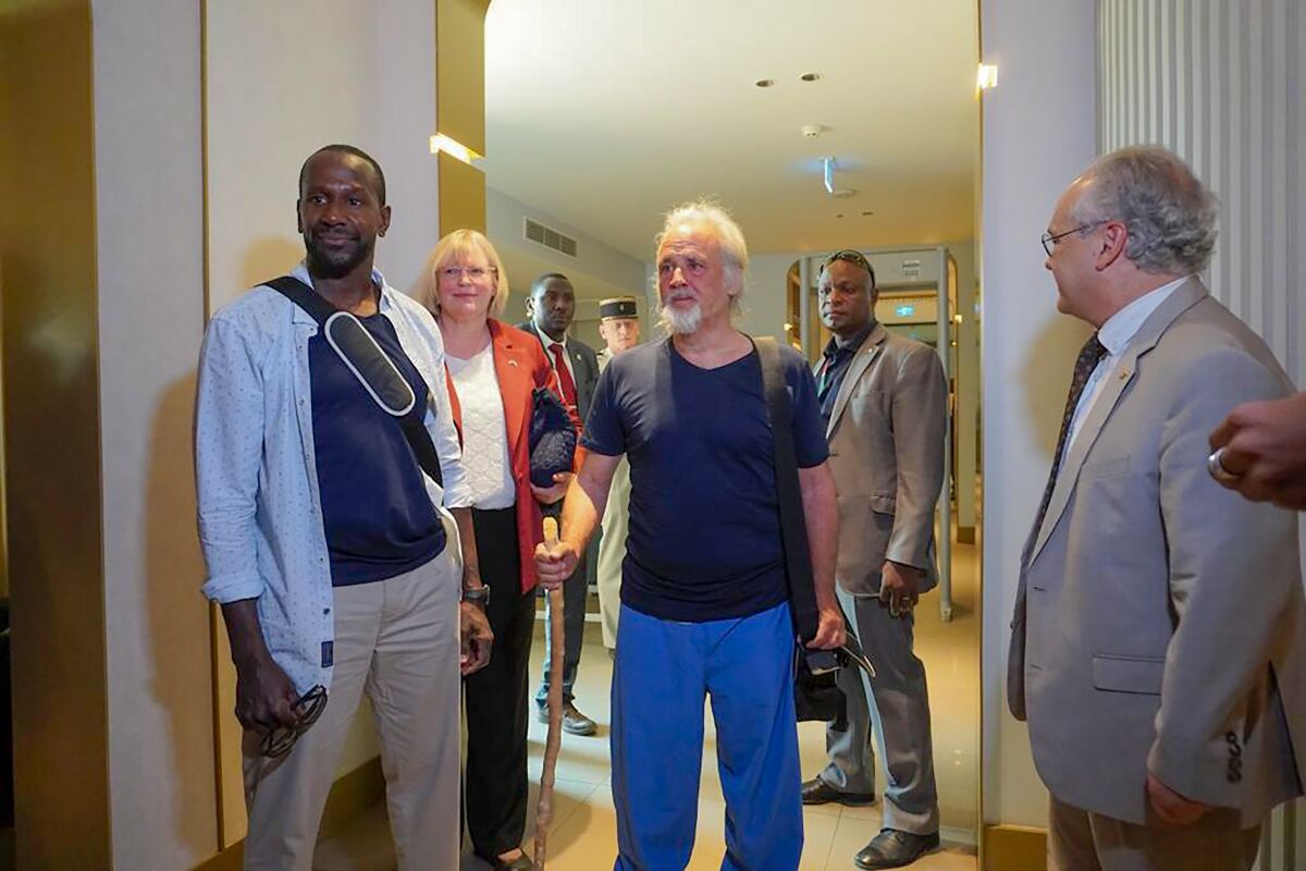 French journalist Olivier Dubois, left, and American aid worker Jeffery Woodke, center, arrive at the VIP lounge at the airport in Niamey, Niger, Monday March 20, 2023. Woodke was held by Islamic extremists in West Africa for more than six years and Dubois was abducted almost two years ago. The two men were the highest-profile foreigners known to be held in the region, and their release was the largest since a French woman and two Italian men were freed together in Mali back in Oct. 2020. (AP Photo/Judith Besnard)