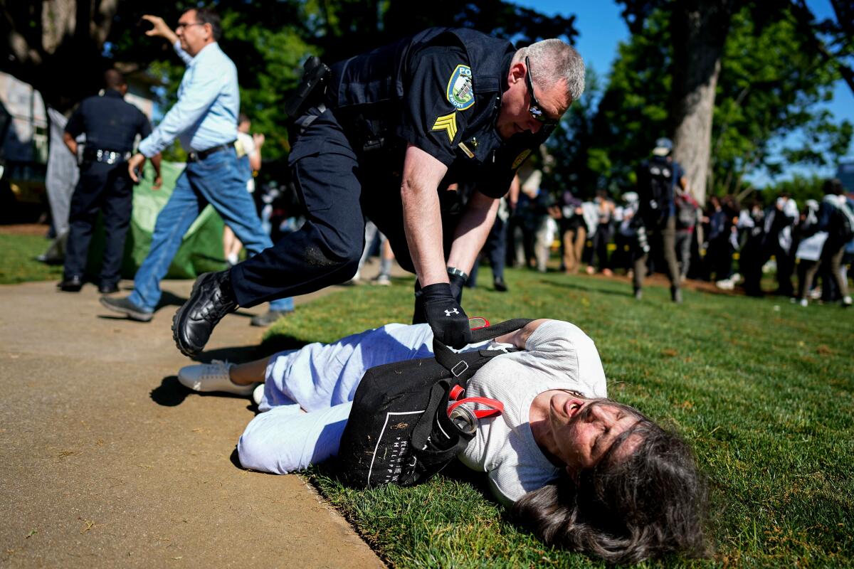 A police officer bends over a protester lying on the grass